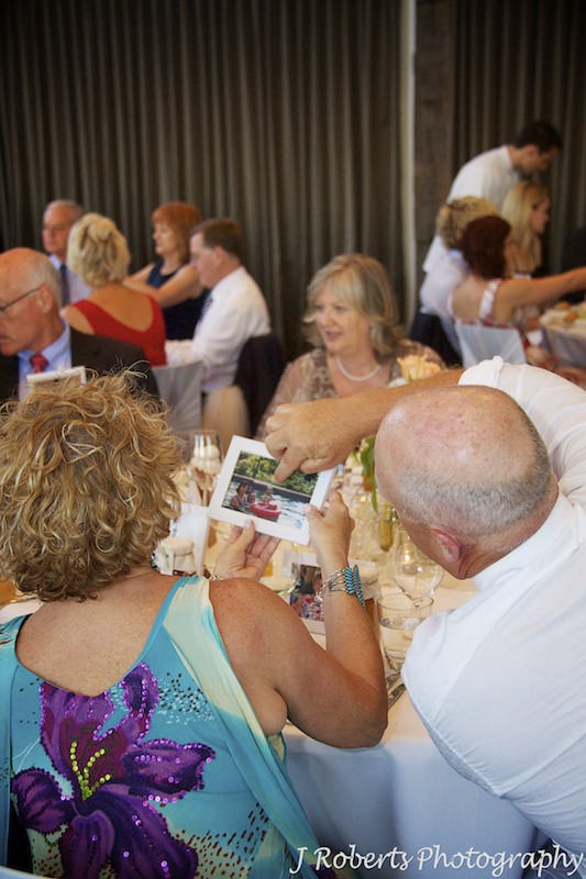 Guests pointing at photographs given to them at wedding - wedding photography sydney